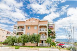 a pink apartment building with balconies and trees at Apartments Peris Resort in Novalja +15 photos