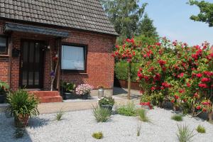 ein Backsteinhaus mit roten Blumen davor in der Unterkunft Haus Clara in Husby