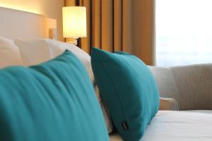 ein blaues Kissen auf einem Bett in einem Hotelzimmer in der Unterkunft WestCord Hotel Noordsee in Nes