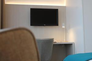 a flat screen tv hanging on a wall with a chair at WestCord Hotel Noordsee in Nes