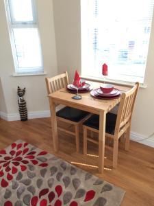 a wooden table with two chairs and a cat sitting in a room at The Custards in Shanklin