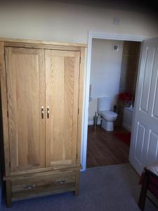 a bathroom with a wooden cabinet and a toilet at The Custards in Shanklin