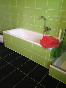 ein grün gefliestes Bad mit einer Badewanne und roten Handtüchern in der Unterkunft Ferienwohnungen zum Hirschberg in Sankt Wendel