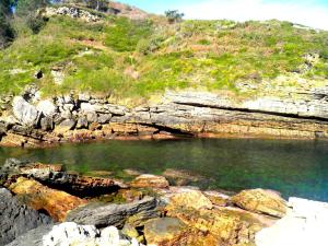 a body of water with rocks and a hill at Casa Rural Postigu in Hondarribia