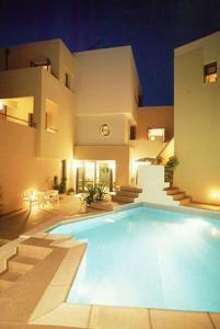 a swimming pool in front of a house at night at Blue Sky Hotel Apartments in Tolo