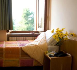 Un dormitorio con una cama con ventana y una mesa con flores en Hotel Fontemaggio, en Asís