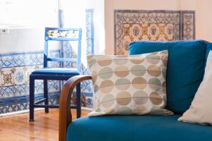 um sofá azul com uma almofada e uma cadeira azul em ALTIDO Classic 3BR home with workspace in Chiado, 2mins from Baixa-Chiado subway em Lisboa