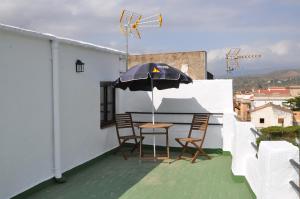 a table and chairs on a balcony with an umbrella at Casa Tamayo in Órgiva