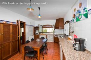 a kitchen with a wooden table and some chairs at Villa Loma Linda in Ogíjares