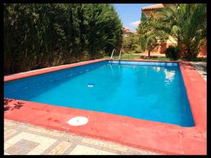 a large blue swimming pool with a red curb at Villa Loma Linda in Ogíjares
