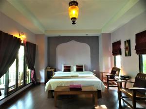 a bedroom with a bed and a table and windows at Baan Thai House in Phra Nakhon Si Ayutthaya