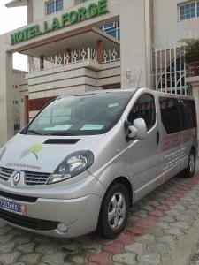 een klein zilveren busje geparkeerd voor een hotel bij Hotel LAFORGE in Abidjan