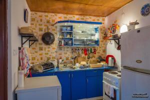 a small kitchen with blue cabinets and a refrigerator at Domek letniskowy Sieraków in Sieraków