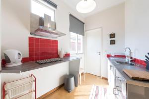 a kitchen with red tiles on the counters and a sink at BmyGuest - Santa Catarina Light Apartment in Porto