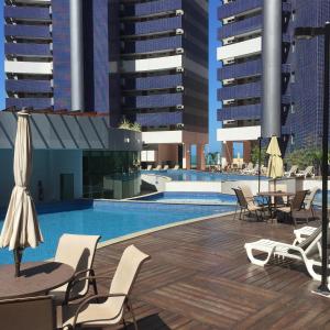 Fortaleza Beach Class Apartments Tower 2 في فورتاليزا: مسبح مع كراسي وطاولات ومباني