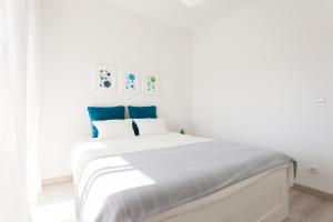 リスボンにあるFLH Marques Modern Flatの白いベッドルーム(青い枕の大きな白いベッド付)