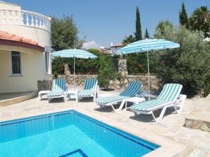 a group of chairs and umbrellas next to a swimming pool at Villa Mutlu in Avsallar