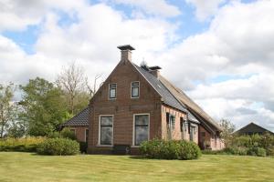 una vieja casa de ladrillo en un campo de hierba en B&B De Warren, en Suawoude