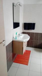 baño con lavabo, espejo y alfombra roja en Sa Mamma e Sole B&B, en Cala Gonone