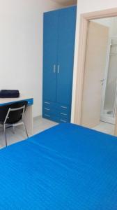 1 dormitorio con cama azul y escritorio en Sa Mamma e Sole B&B, en Cala Gonone