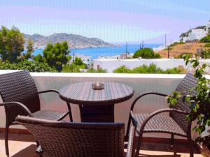 una mesa y sillas en un balcón con vistas al océano en Ios Memories, en Mylopotas