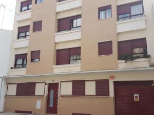 un edificio alto con puertas y ventanas marrones en Vivienda Reina Victoria, en Huelva