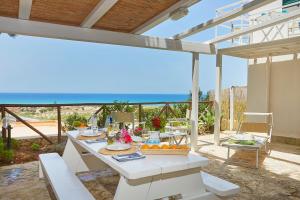 een witte tafel met eten erop met uitzicht op de oceaan bij Appartaville Castellammare del Golfo in Castellammare del Golfo