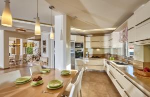a kitchen with a wooden table and white cabinets at Villa EverGreen in Heraklio Town