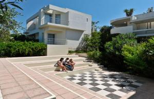 three people sitting on a chessboard in front of a house at Rodon Hotel in Chania