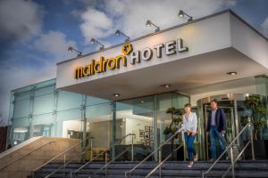 a man and woman walking out of a modern hotel at Maldron Hotel Dublin Airport in Cloghran