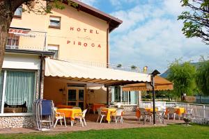 a hotel with tables and chairs in front of a building at Hotel La Piroga in Calceranica al Lago