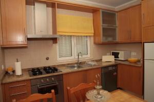 a kitchen with wooden cabinets and a sink and a stove at Casas de Santo António in Odeceixe