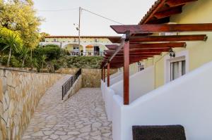 a house with a stone walkway next to a wall at SeaView Apartments in Tsilivi