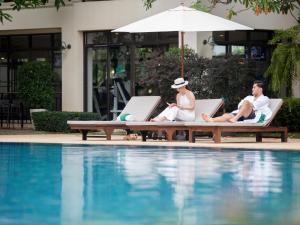 Maneechan Resort - SHA Extra Plus في تشانتابوري: ثلاثة أشخاص يجلسون على كراسي الصالة بجوار حمام السباحة