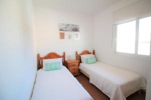 two beds in a room with white walls and a window at Villa Sofia in San Antonio