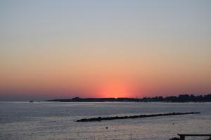 a sunset over a body of water with a pier at Amphora Hotel & Suites in Paphos