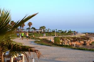 a group of people walking down a path near the beach at Amphora Hotel & Suites in Paphos