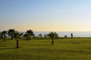a group of people walking on a beach with palm trees at Amphora Hotel & Suites in Paphos