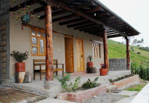 a house with a porch with a table and a bench at Hostal el castillo ingapirca in Ingapirca
