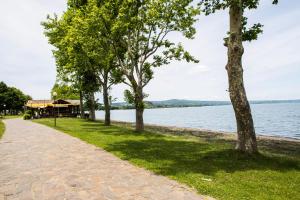 a walkway next to a lake with trees at Lako Hostel in Capodimonte
