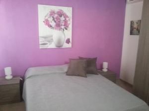a purple bedroom with a bed with a vase of flowers at Appartamento Vincenzina in Lampedusa