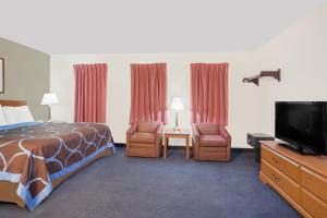 a hotel room with a bed and two chairs and a television at Super 8 by Wyndham Middletown in Middletown