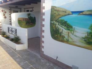 two paintings on the side of a building with a painting on the wall at Appartamento Vincenzina in Lampedusa