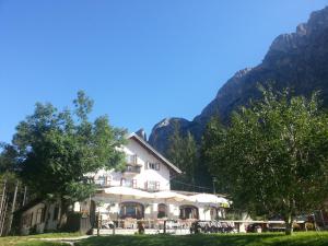 un gran edificio blanco con montañas en el fondo en Hotel Fiames en Cortina dʼAmpezzo