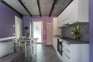 cocina con paredes de color púrpura, mesa y sofá en Il Portico, en Baveno