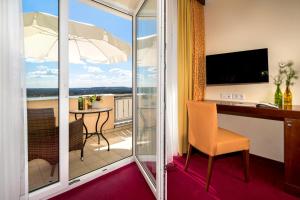 a room with a balcony with a desk and a table at Hotel-Restaurant Distlerhof in Leinburg