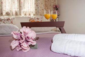 un letto con due bicchieri di succo d'arancia e un fiore sopra di Kyriaki's Cozy Apartments ad Agia Marina Nea Kydonias