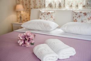 un letto con due asciugamani e un fiore sopra di Kyriaki's Cozy Apartments ad Agia Marina Nea Kydonias