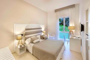a white bedroom with a bed and a window at Hotel Rivage in Sorrento