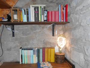 una estantería con libros y una lámpara sobre una mesa en La casa nel bosco-senza auto en Ponte della Venturina